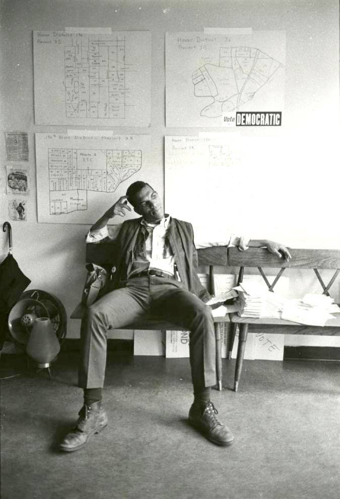Ivanhoe Donaldson sitting in a campaign office, on the wall above him are maps of the voting districts around Atlanta